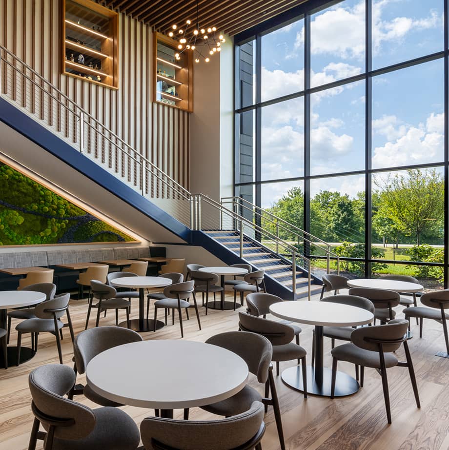 Interior entrance of 815 Building with stair case next to curtain window wall. Tables and chairs in the atrium.