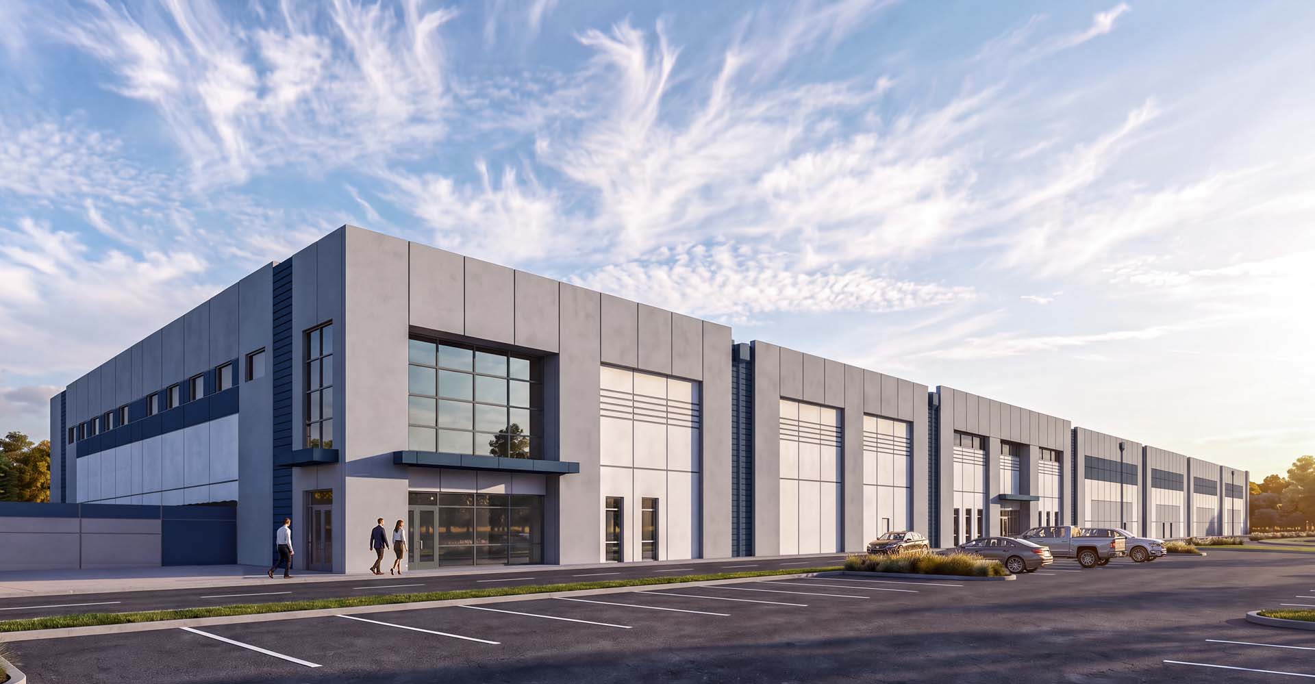Industrial building exterior with tilt-up concrete panels, glass entrance, and loading dock doors.