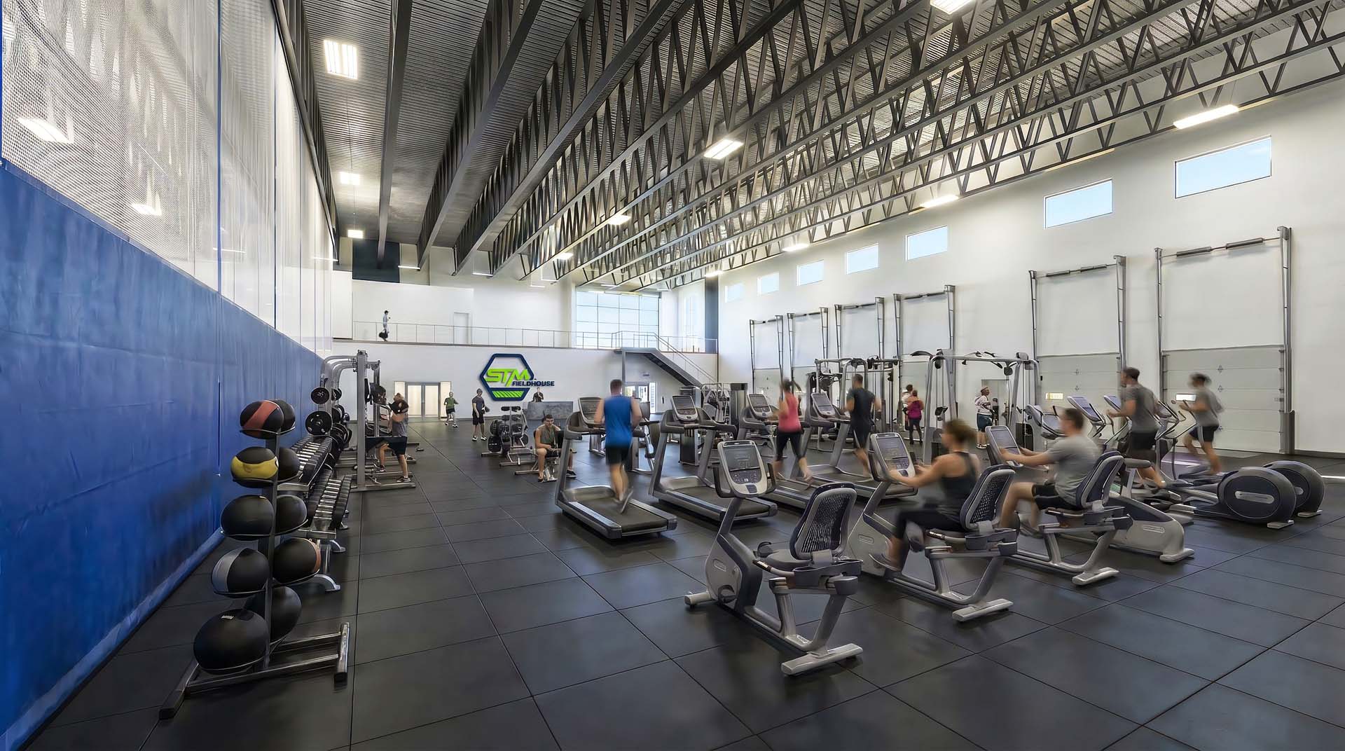 Fitness gym area with treadmills, exercise bikes, and free weights inside STM Fieldhouse.