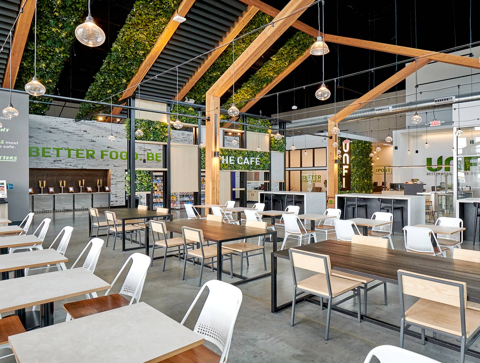 Interior view if UNFI cafe with seating underneath greenery and wooden trusses.