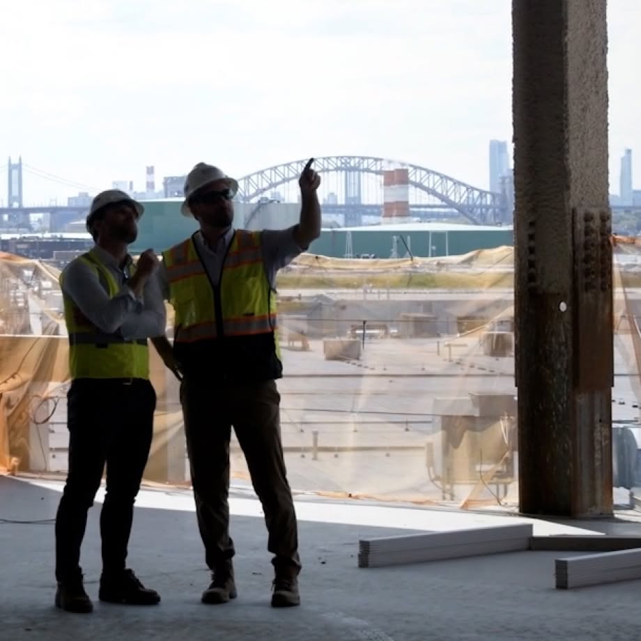 Two team members on an elevated jobsite with city scape in the background.