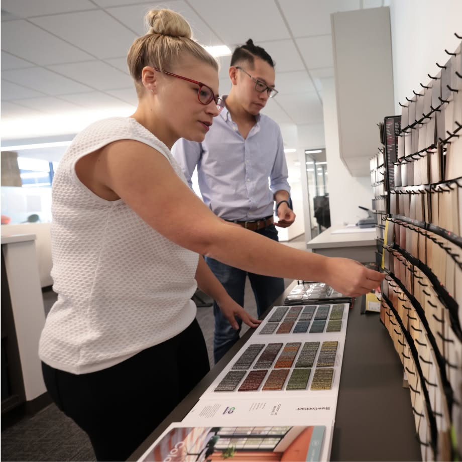 Two team members looking at samples from a wall in an office.
