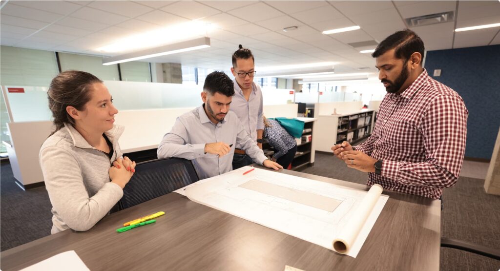 Group of architects working on a printed drawing.