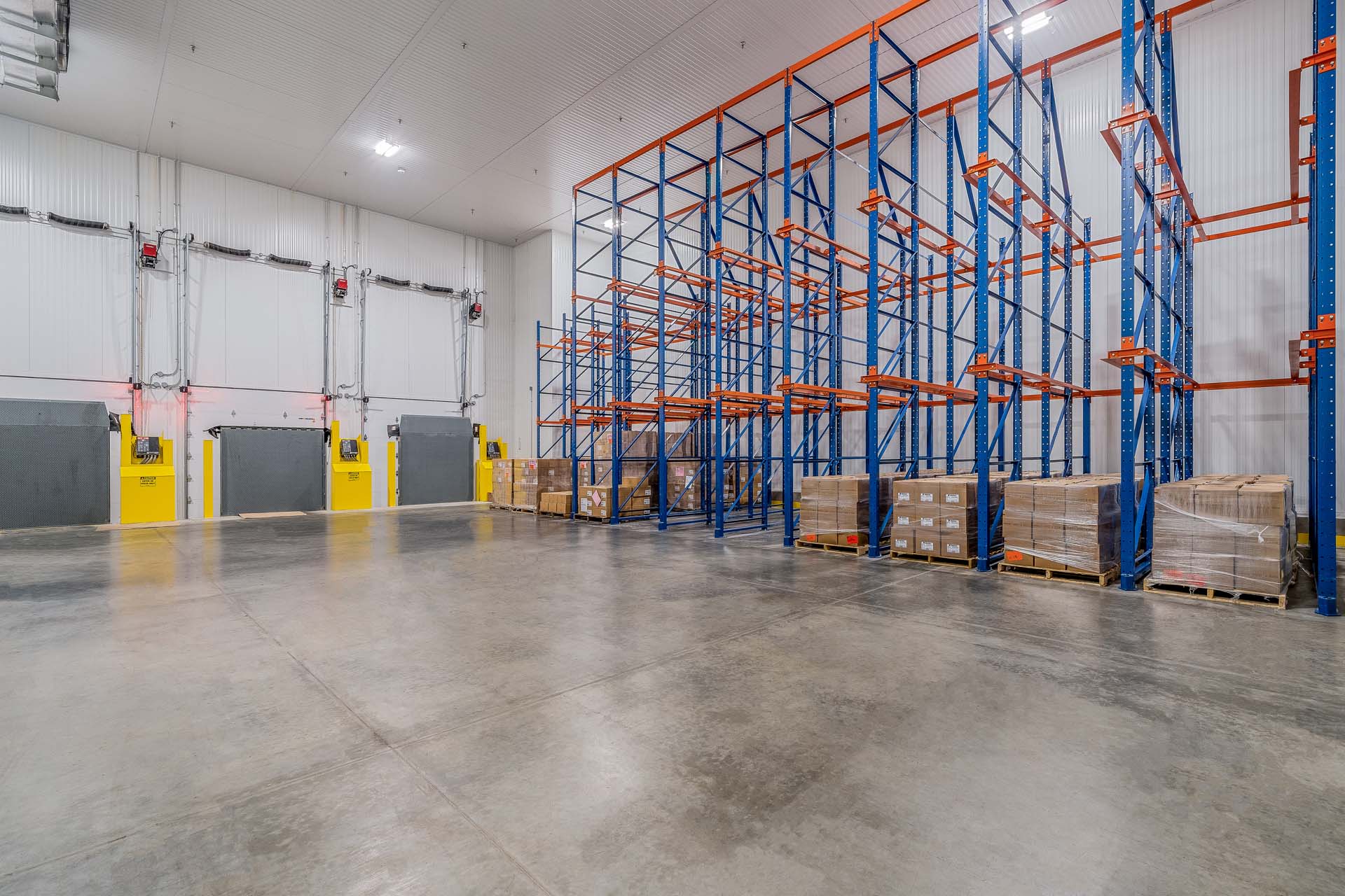 Cold storage warehouse with pallet racking and loading dock doors.