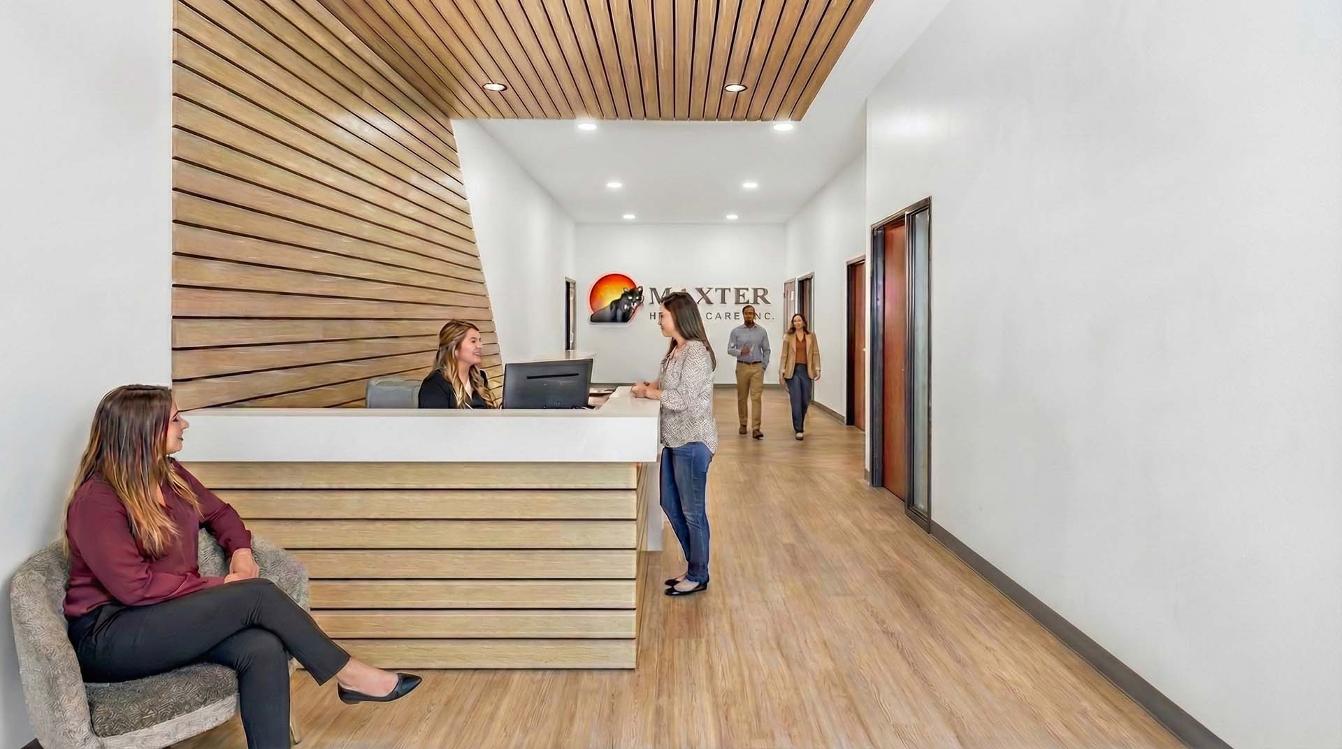 Reception lobby with wood slat wall, front desk, and hallway to office suites.