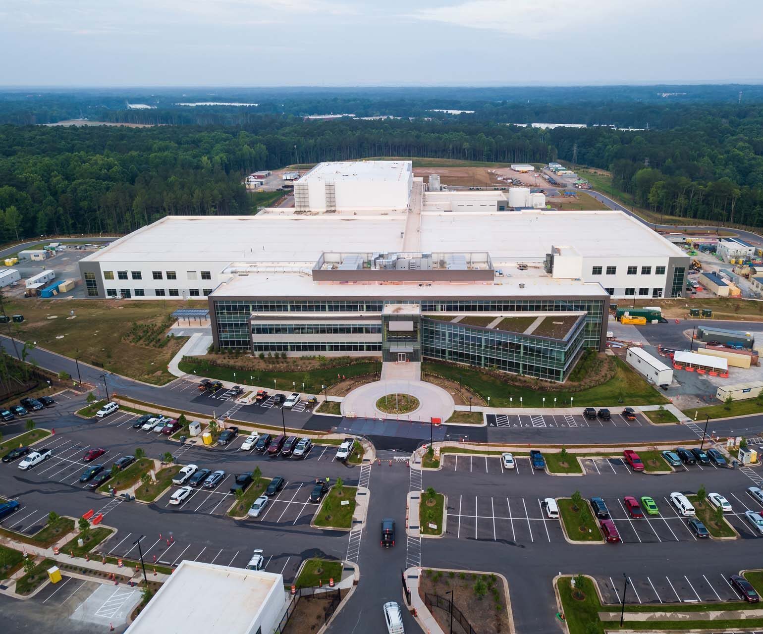 Aerial view of manufacturing campus with glass entrance and large parking lot.
