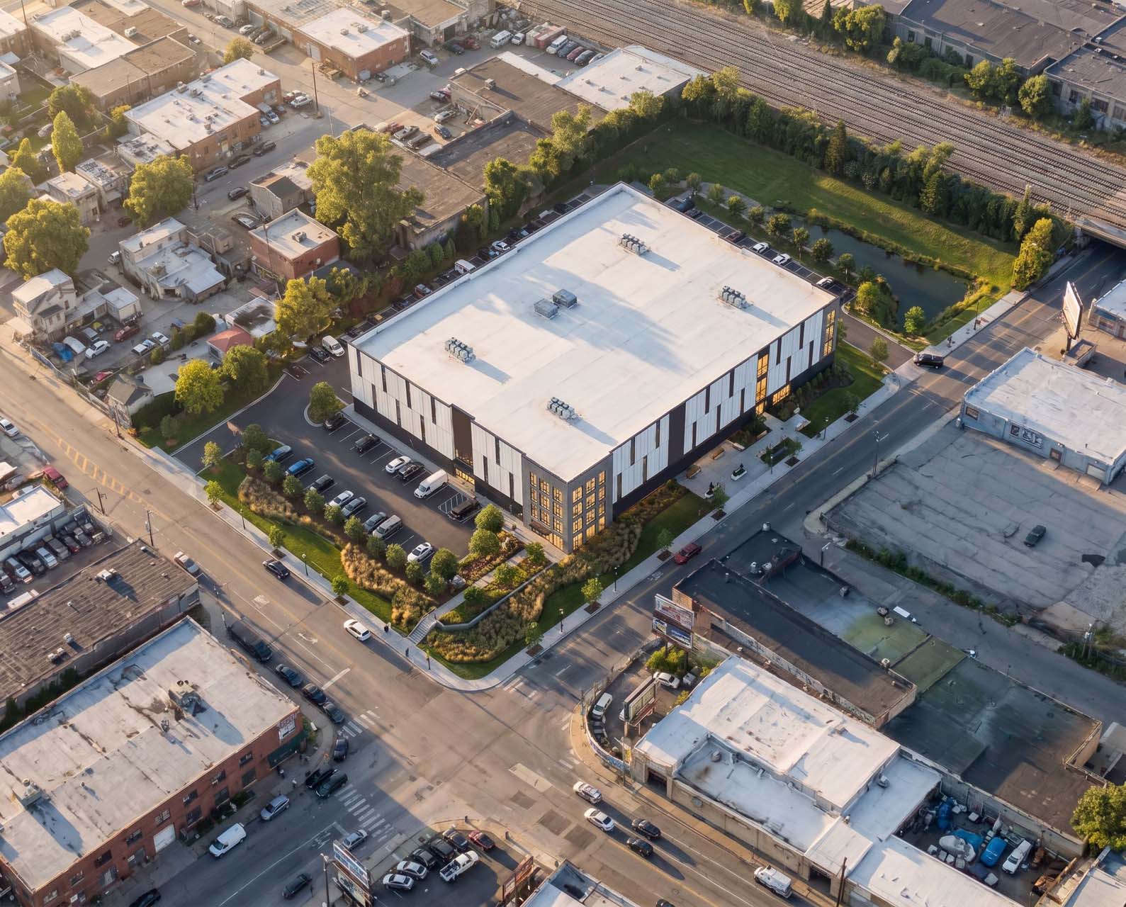 Aerial view of self storage building on urban corner lot with parking and landscaping.
